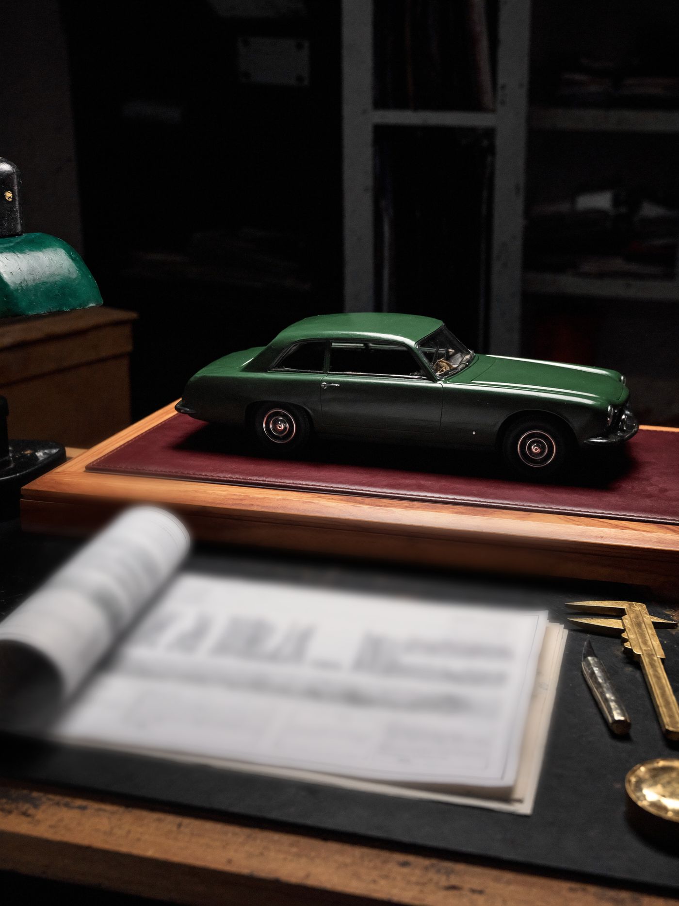 The quartermaster's workbench — a scale model of a grand tourer among brass tools and drawings