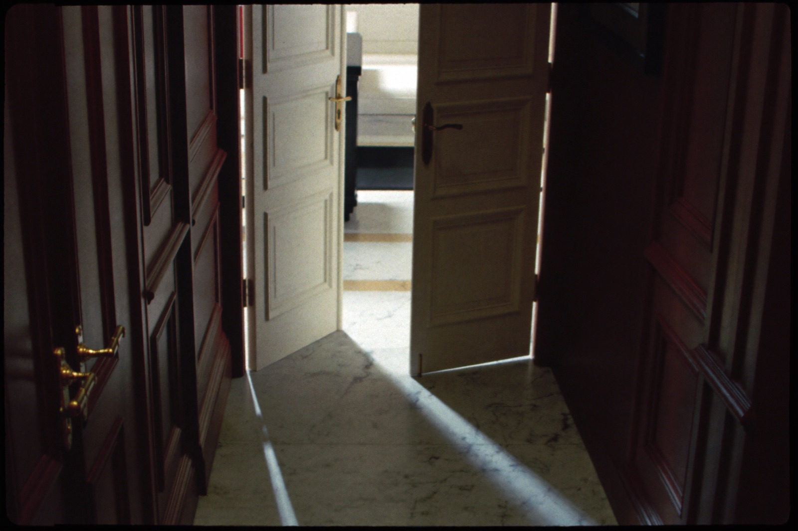 White double doors ajar with light spilling into a dark corridor