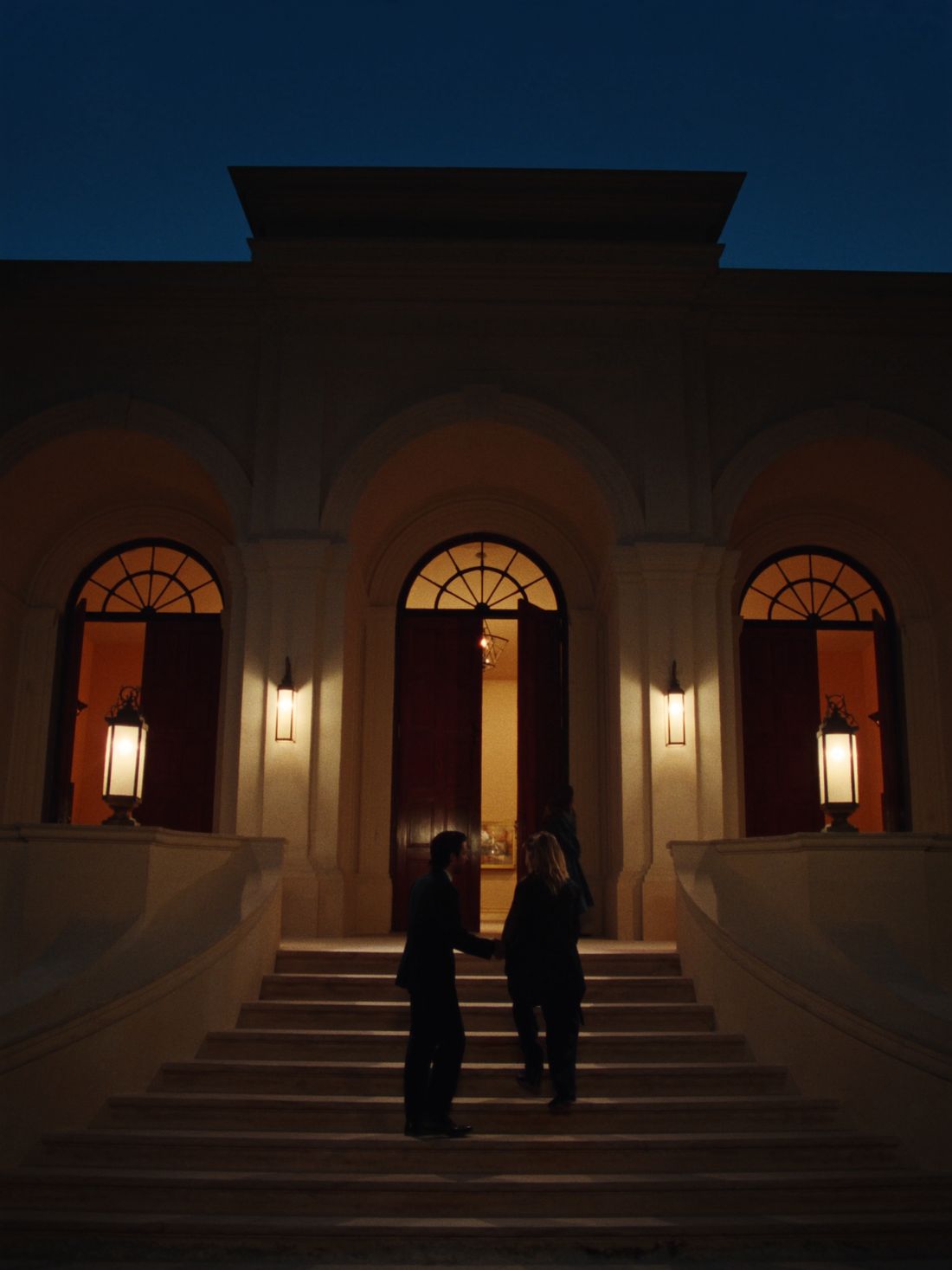 A handshake on the lantern-lit clubhouse steps at dusk