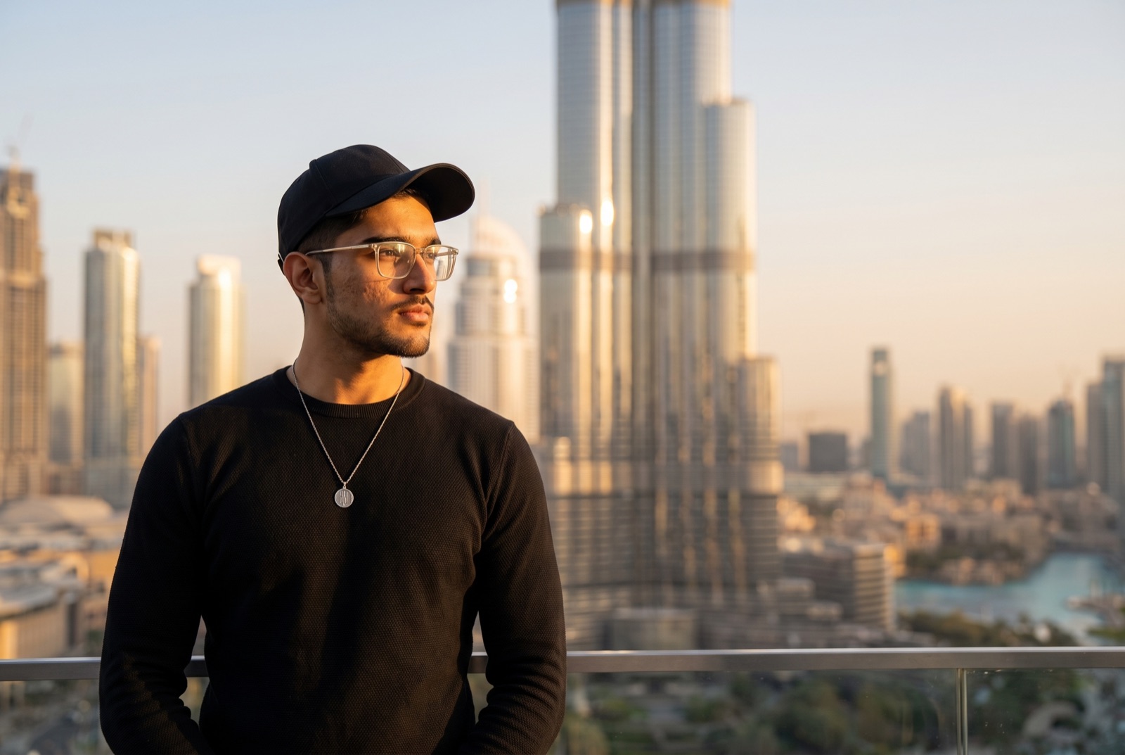 Muhammad Fahad on a Dubai terrace at golden hour, the Burj Khalifa and the Downtown skyline behind him