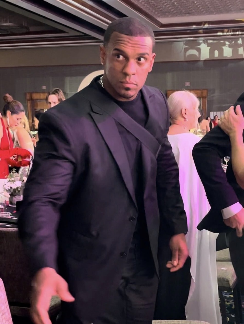 Piki in a dark suit at a gala, scanning the room — the focus every room needs
