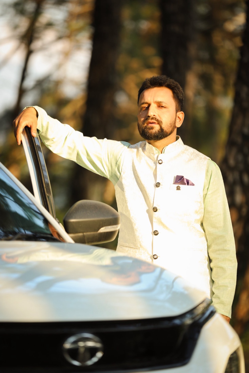 Rahul Dhiman standing beside his car on a forest road in Himachal Pradesh