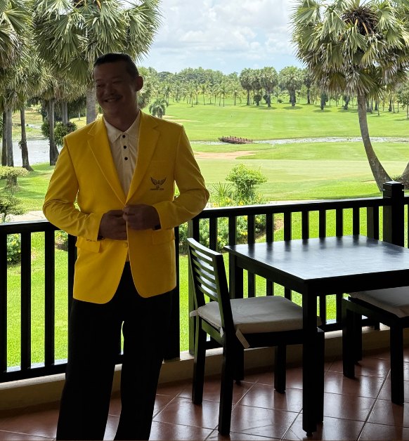 The first real gold jacket — worn on a terrace railing above a tropical golf course, the crest on the chest