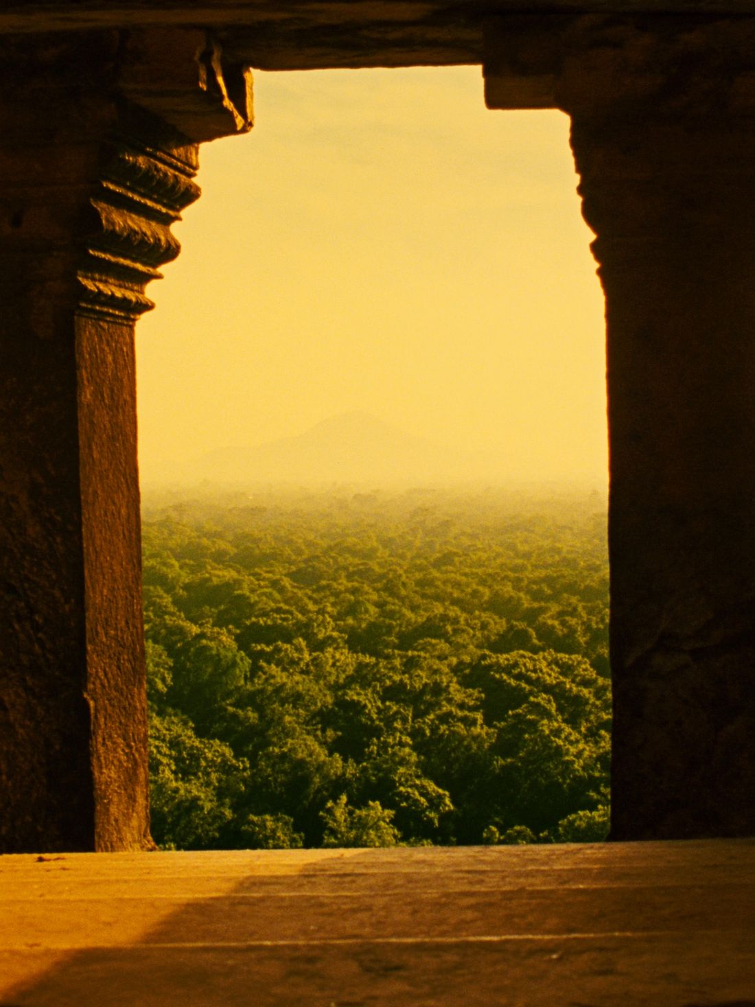 A temple doorway opening onto a golden sunrise over endless jungle