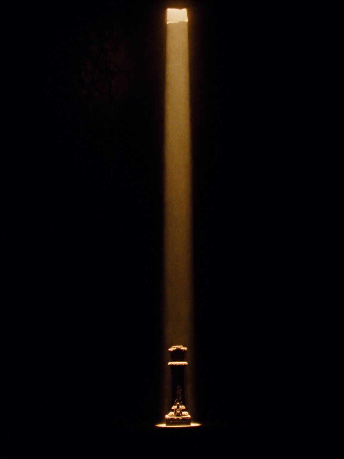 A single shaft of dawn light finding a lone pillar in the dark sanctum