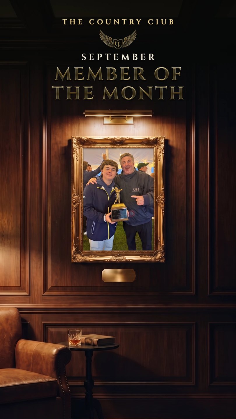 The Country C1ub September Member of the Month plate: Craig and his son holding a trophy, framed in gold on a wood-panelled wall.