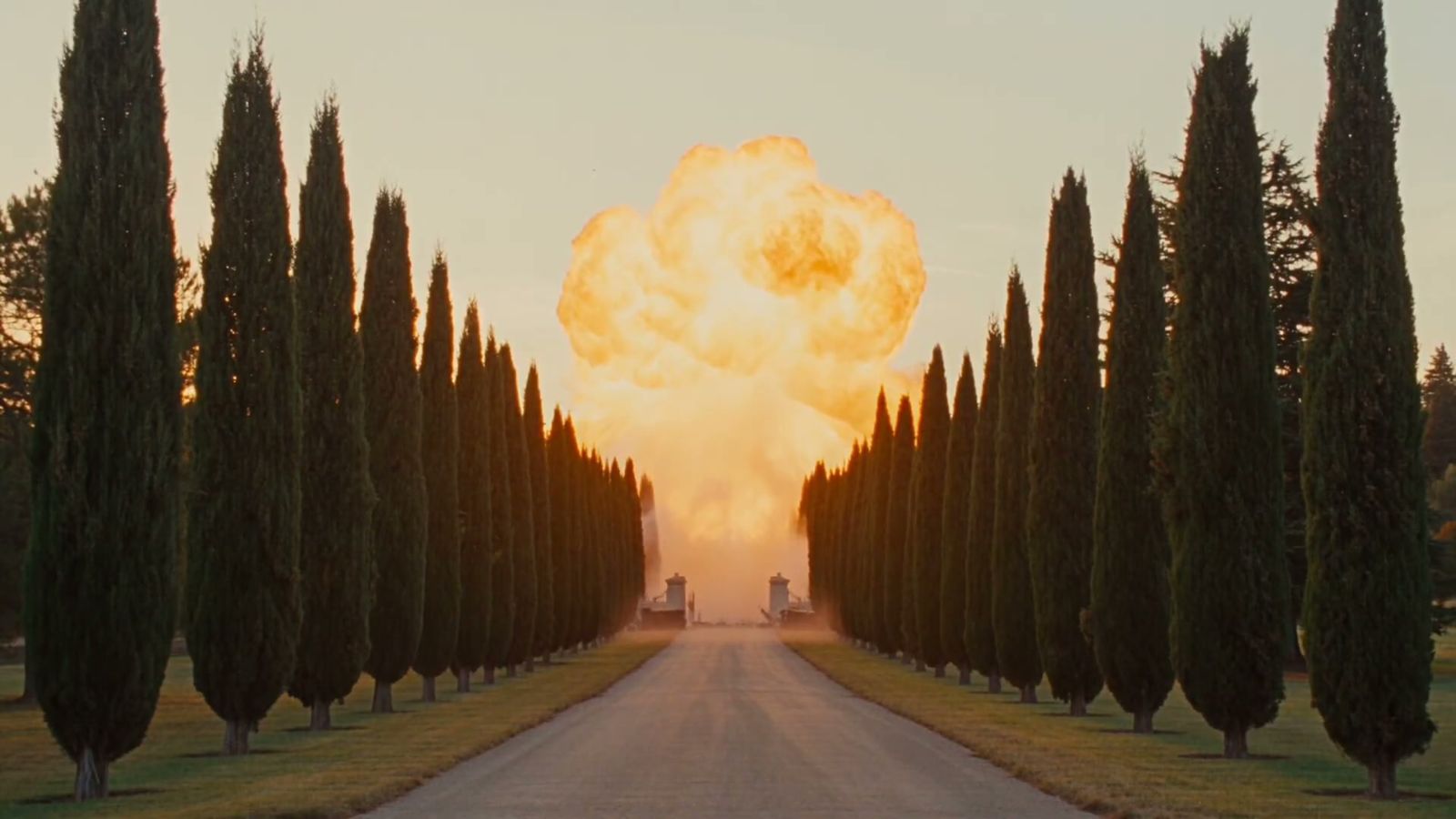 A fireball rising at the end of the cypress-lined drive at sunset