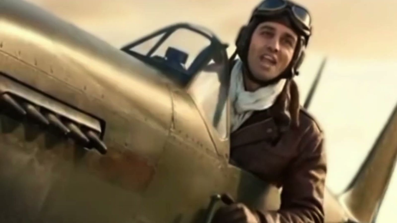 A pilot in vintage flying gear smiling beside his warbird