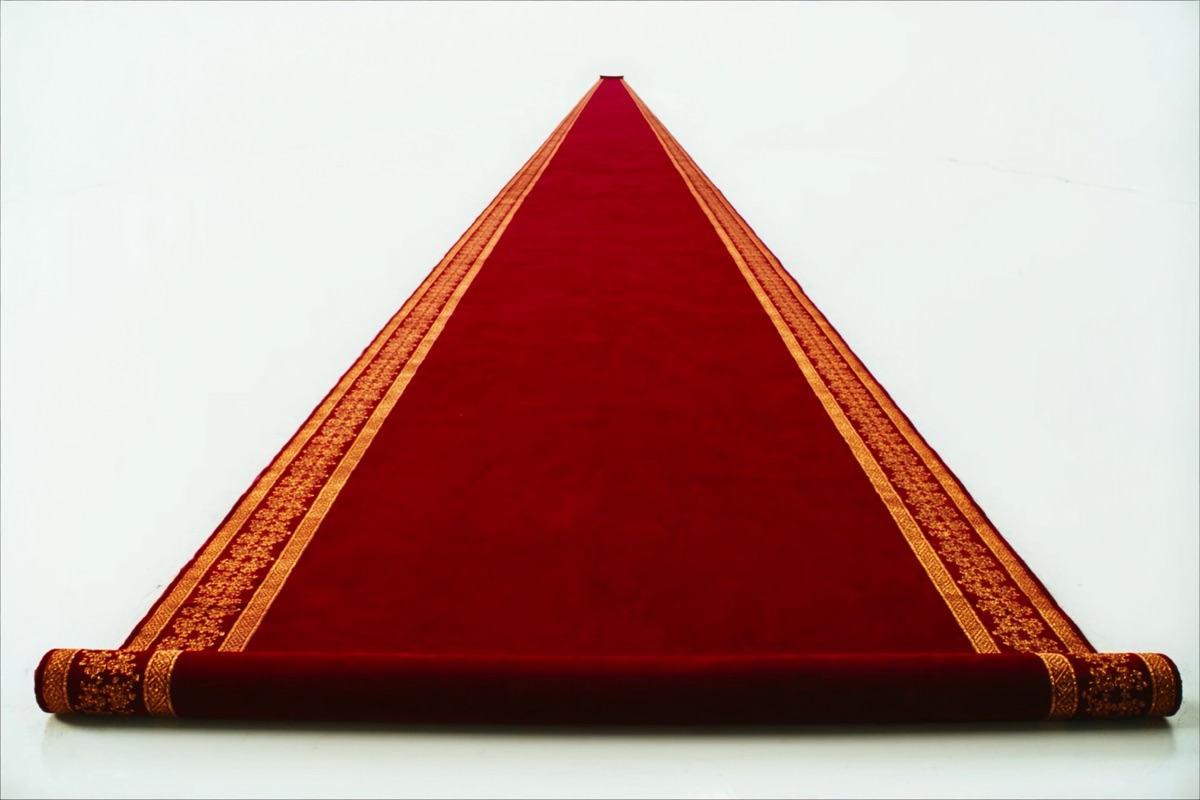 A red carpet with gold trim rolled out across the infinite white floor toward the horizon