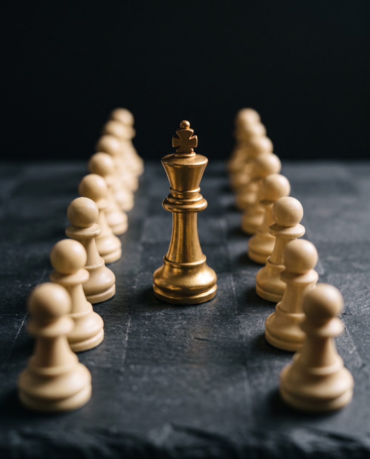 A single gold chess piece standing among cream pawns