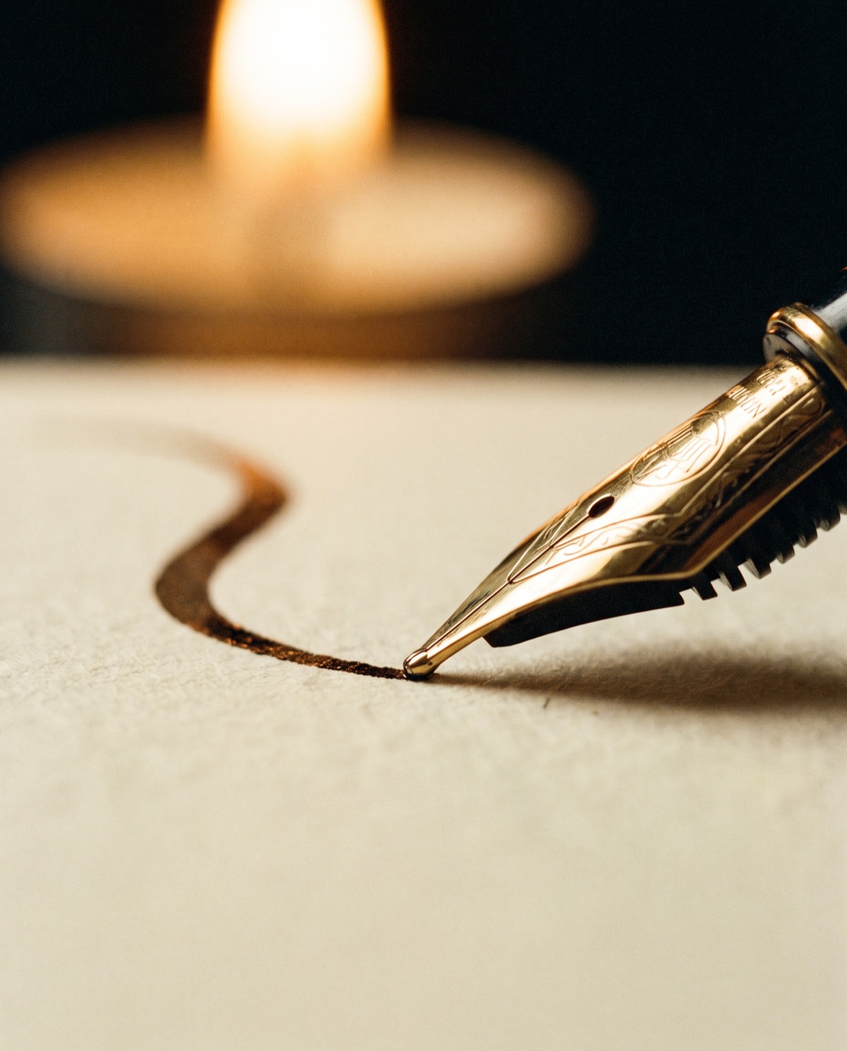 A fountain pen nib trailing a flourish of gold ink in the dark