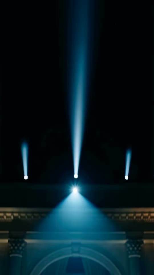 White searchlight beams rising into the night sky above the gala